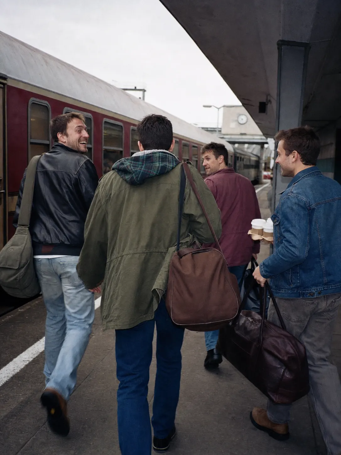 Freunde laufen mit Wochenendtaschen am Bahnsteig zu ihrem Zug